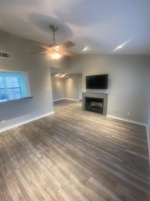 unfurnished living room featuring baseboards, a fireplace, visible vents, and wood finished floors