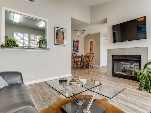 living area with a fireplace, light wood-style flooring, and baseboards