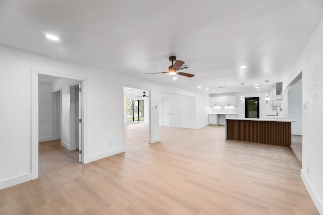 unfurnished living room with ceiling fan and light wood-type flooring