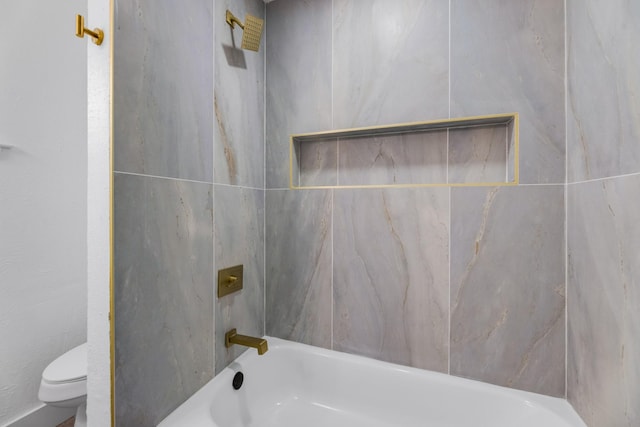 bathroom with tiled shower / bath combo and toilet