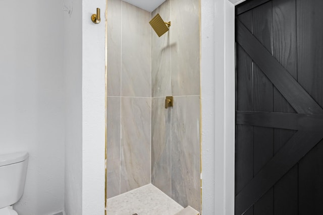 bathroom featuring toilet and a tile shower