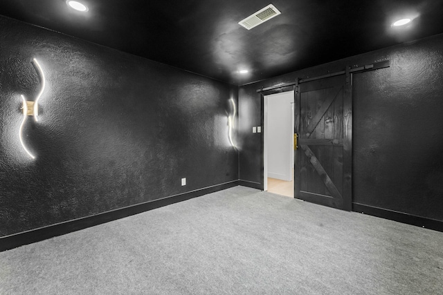 spare room featuring a barn door and light carpet