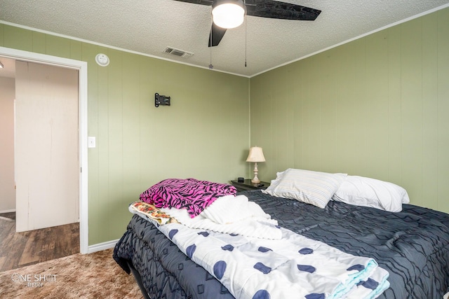 bedroom with ornamental molding, ceiling fan, and a textured ceiling