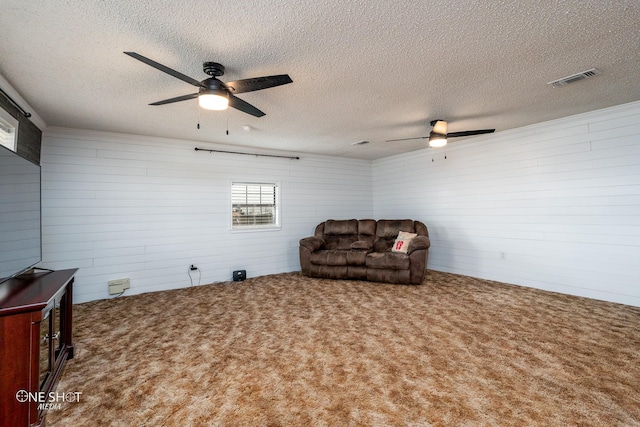 living area featuring a textured ceiling, ceiling fan, and carpet