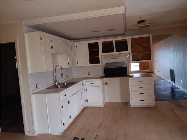 kitchen with light hardwood / wood-style floors, sink, a textured ceiling, and white cabinets