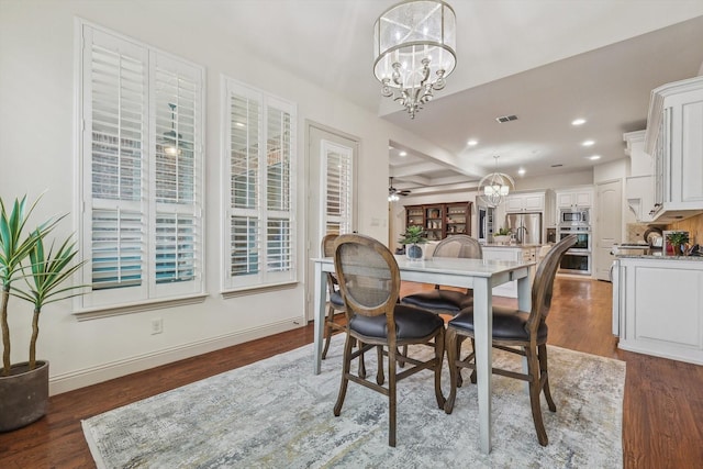 dining room with ceiling fan with notable chandelier and dark hardwood / wood-style floors