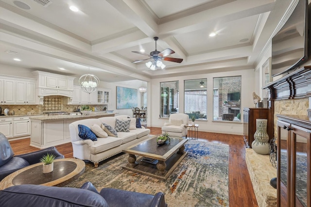 living room with ceiling fan with notable chandelier, beamed ceiling, dark hardwood / wood-style flooring, ornamental molding, and coffered ceiling