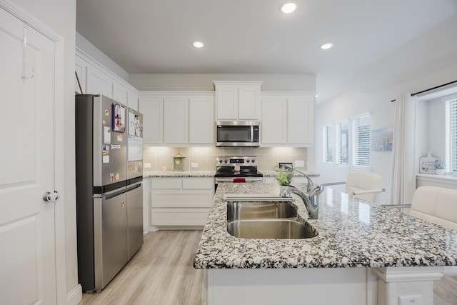 kitchen with stainless steel appliances, white cabinetry, a sink, and tasteful backsplash