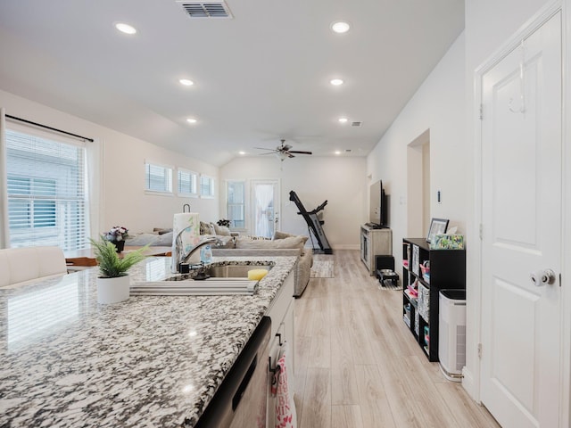 kitchen featuring recessed lighting, visible vents, open floor plan, a sink, and light stone countertops