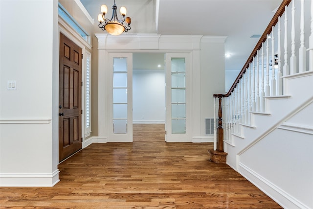 foyer with crown molding, hardwood / wood-style floors, and a chandelier