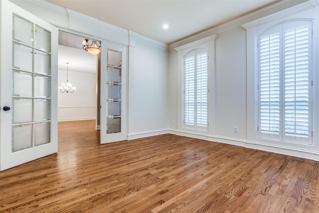 spare room featuring crown molding, a wealth of natural light, hardwood / wood-style floors, and french doors