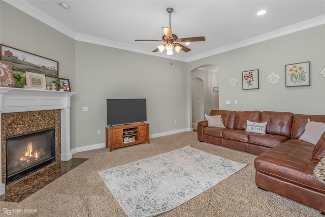 living room featuring a premium fireplace, ornamental molding, and ceiling fan