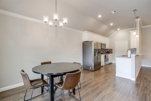 dining room with sink, vaulted ceiling, and ornamental molding