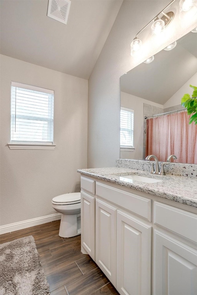 bathroom featuring vaulted ceiling, hardwood / wood-style floors, vanity, toilet, and a shower with curtain