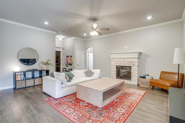 living room featuring crown molding, ceiling fan, and a fireplace