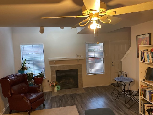 living room featuring ceiling fan, dark hardwood / wood-style flooring, and a tile fireplace