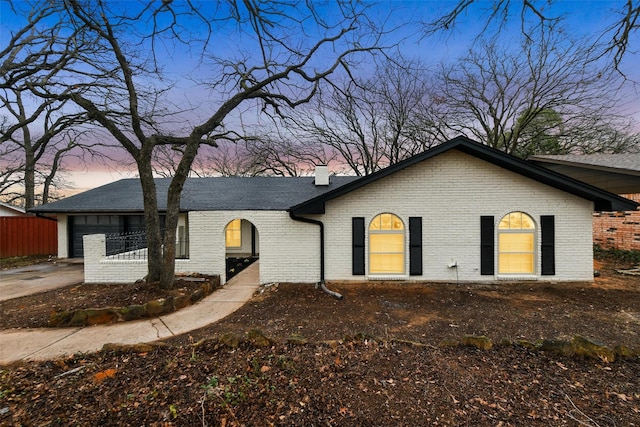 ranch-style house featuring a chimney, fence, concrete driveway, and brick siding