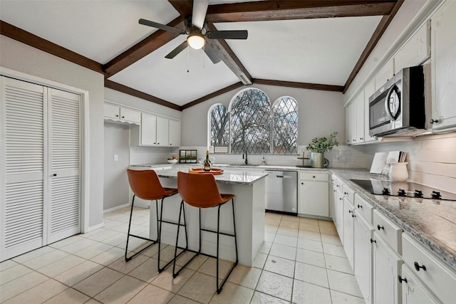 kitchen featuring tasteful backsplash, a kitchen island, appliances with stainless steel finishes, a kitchen bar, and white cabinetry