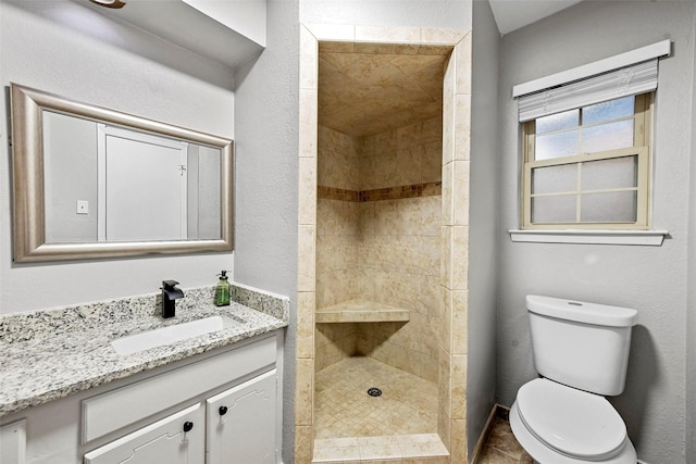 full bathroom featuring vanity, a tile shower, and toilet