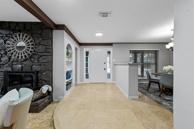 tiled entryway with baseboards, visible vents, and a stone fireplace