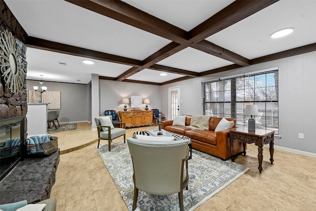 living area with baseboards, coffered ceiling, a stone fireplace, a chandelier, and beam ceiling