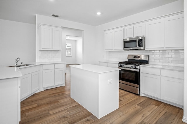 kitchen featuring appliances with stainless steel finishes, white cabinets, and light wood-type flooring