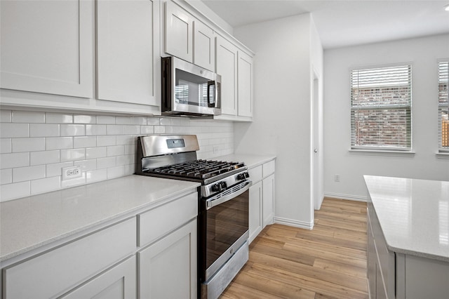 kitchen featuring stainless steel appliances, tasteful backsplash, white cabinets, and light wood-type flooring