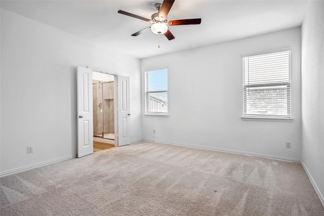 unfurnished bedroom with multiple windows, connected bathroom, light carpet, and ceiling fan