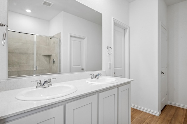 bathroom featuring wood-type flooring, an enclosed shower, and vanity