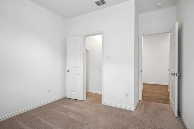 unfurnished bedroom with a spacious closet, light colored carpet, and a closet