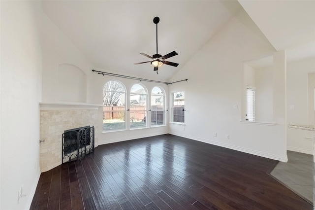 unfurnished living room with ceiling fan, dark hardwood / wood-style flooring, a tiled fireplace, and high vaulted ceiling