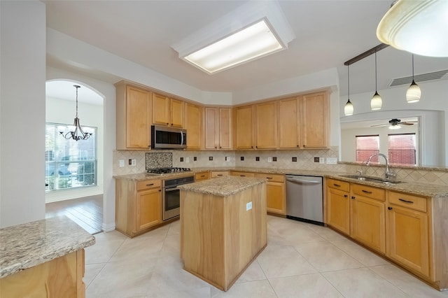 kitchen with sink, hanging light fixtures, light brown cabinets, a kitchen island, and stainless steel appliances