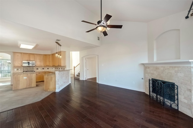 kitchen with dark hardwood / wood-style flooring, ceiling fan, backsplash, light brown cabinetry, and a brick fireplace