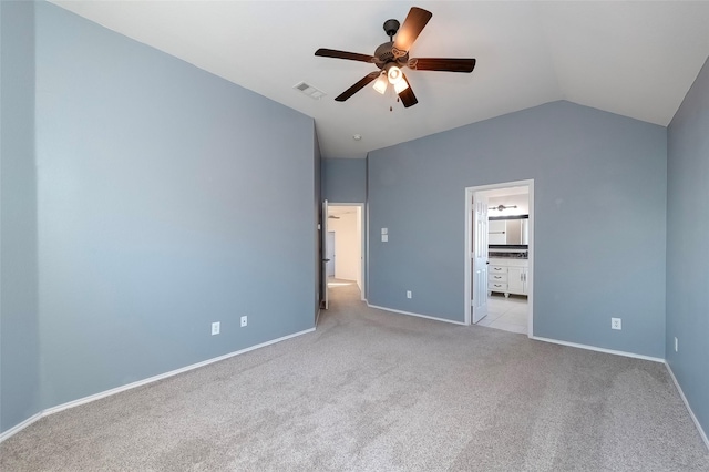 unfurnished bedroom with ceiling fan, ensuite bathroom, vaulted ceiling, and light carpet