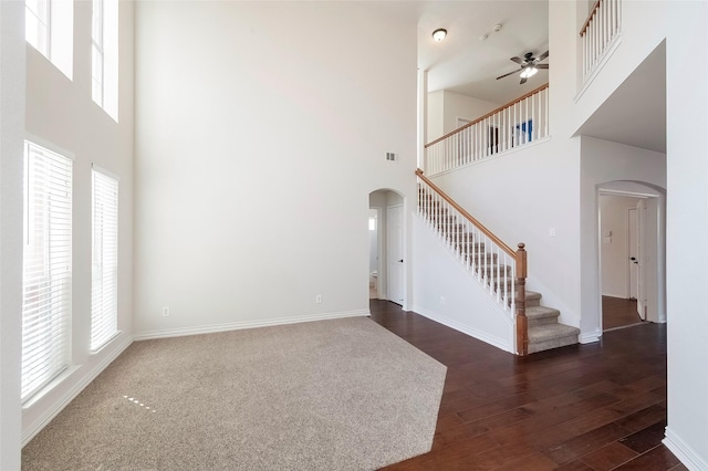 unfurnished living room featuring a high ceiling, ceiling fan, and dark hardwood / wood-style flooring