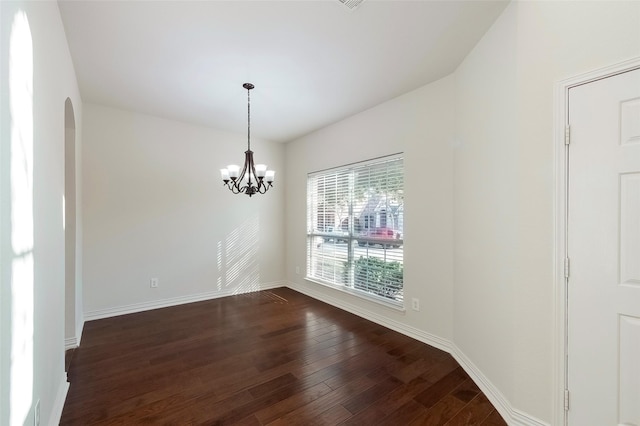 empty room with dark hardwood / wood-style flooring and an inviting chandelier