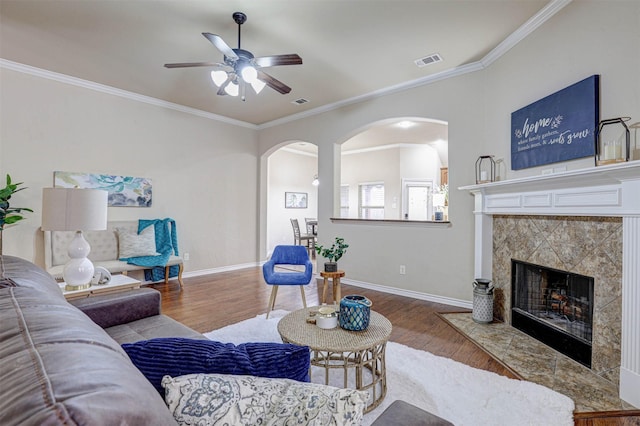 living room featuring crown molding, wood-type flooring, a premium fireplace, and ceiling fan