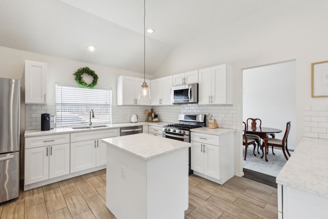 kitchen with decorative light fixtures, sink, white cabinets, light stone counters, and stainless steel appliances