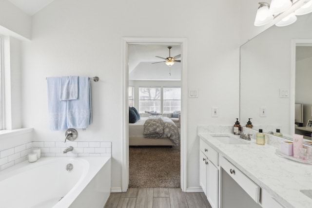 bathroom featuring vaulted ceiling, vanity, a bath, hardwood / wood-style flooring, and ceiling fan