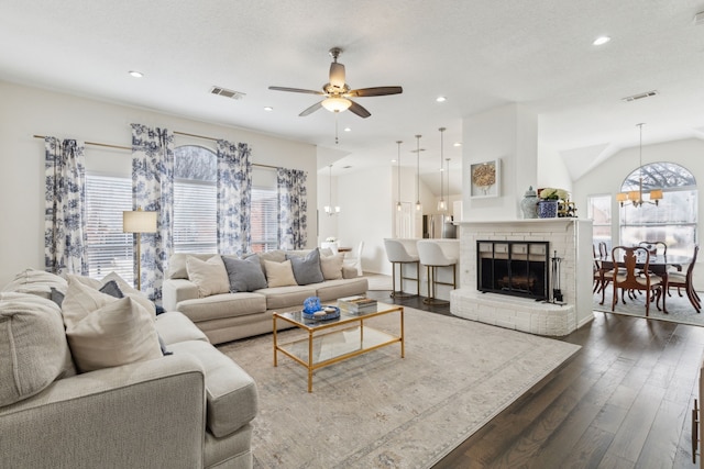 living room featuring dark wood-type flooring, vaulted ceiling, a textured ceiling, and ceiling fan with notable chandelier