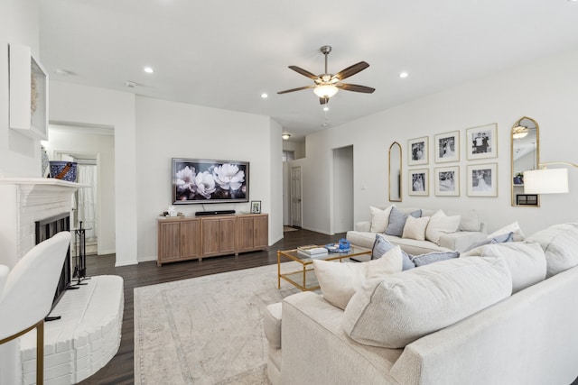 living room featuring a brick fireplace, dark hardwood / wood-style floors, and ceiling fan