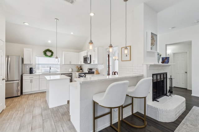 kitchen with sink, white cabinetry, hanging light fixtures, appliances with stainless steel finishes, and kitchen peninsula