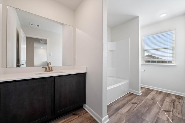 bathroom featuring wood-type flooring, tub / shower combination, and vanity