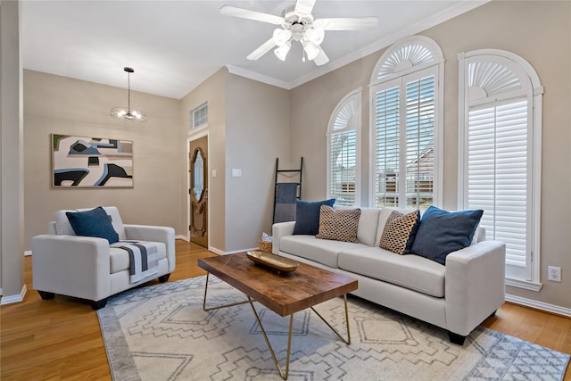 living room featuring ceiling fan with notable chandelier, light hardwood / wood-style flooring, and ornamental molding