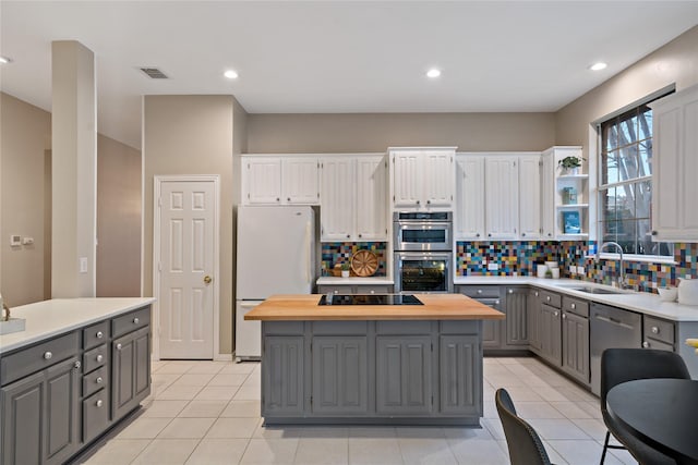 kitchen with stainless steel appliances, white cabinetry, sink, and gray cabinetry