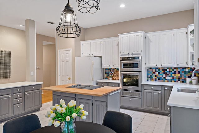 kitchen featuring sink, white cabinetry, decorative light fixtures, white fridge, and black electric stovetop