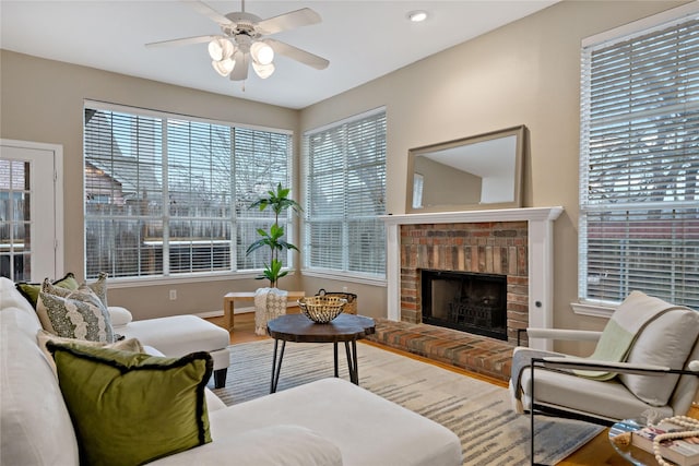 living room with hardwood / wood-style flooring, ceiling fan, and a brick fireplace