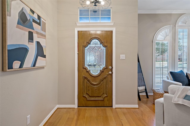 foyer entrance featuring ornamental molding, a chandelier, and light hardwood / wood-style floors