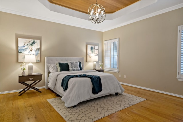 bedroom with crown molding, light hardwood / wood-style flooring, an inviting chandelier, and a tray ceiling