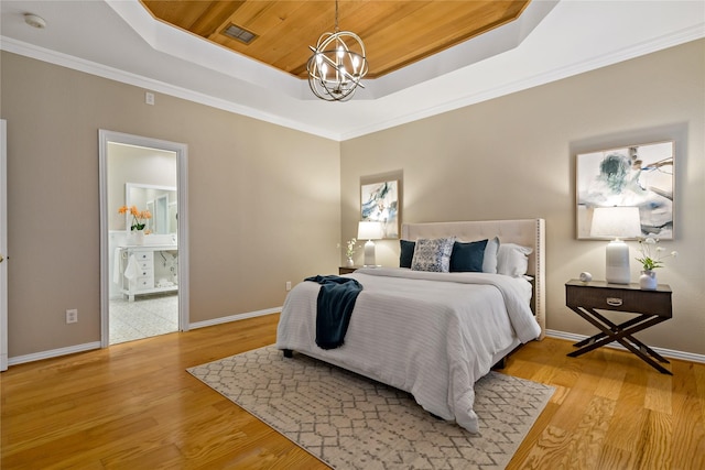 bedroom featuring a notable chandelier, light hardwood / wood-style floors, and a tray ceiling